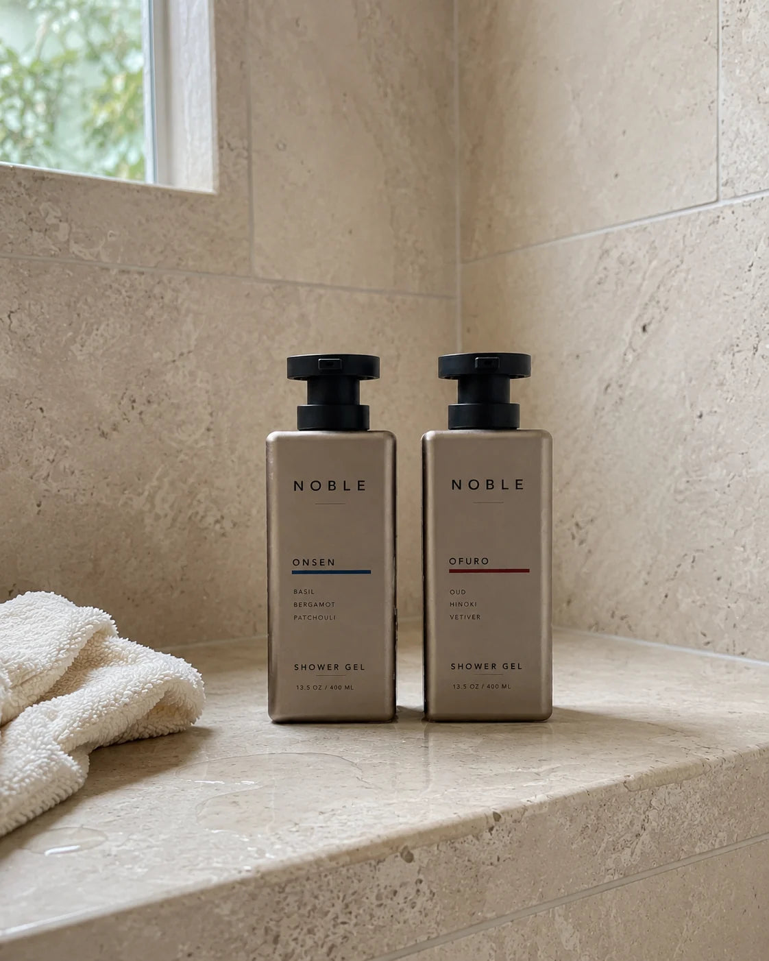 ONSEN and OFURO 13.5 oz metal bottles on a light stone shower bench by a window, a white towel beside them
